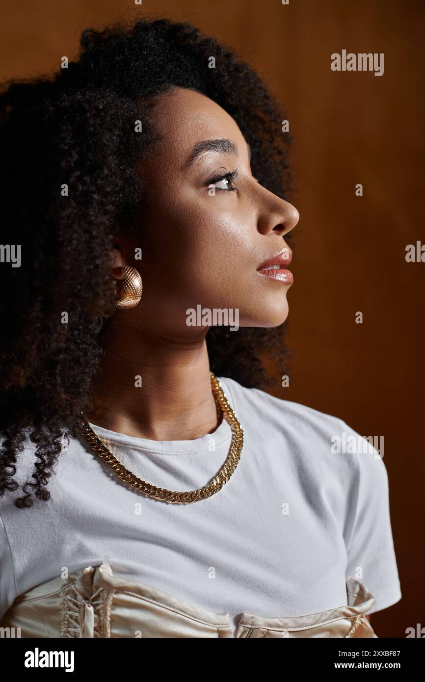 A fashionable African American woman with curly hair poses in a studio ...