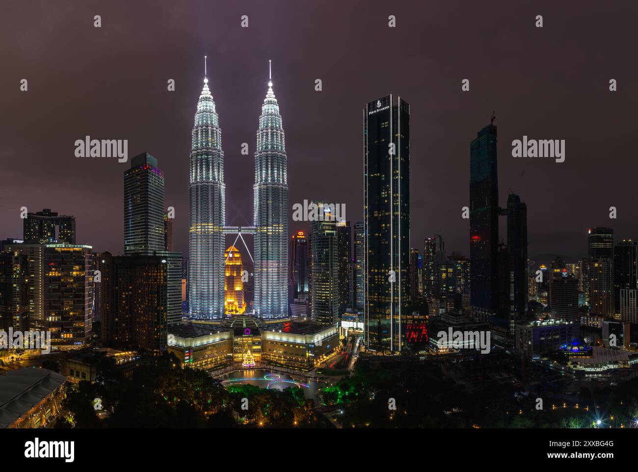 A picture of the Petronas Twin Towers, the KLCC Park water and light fountain show and the Suria KLCC shopping center at night. Stock Photo