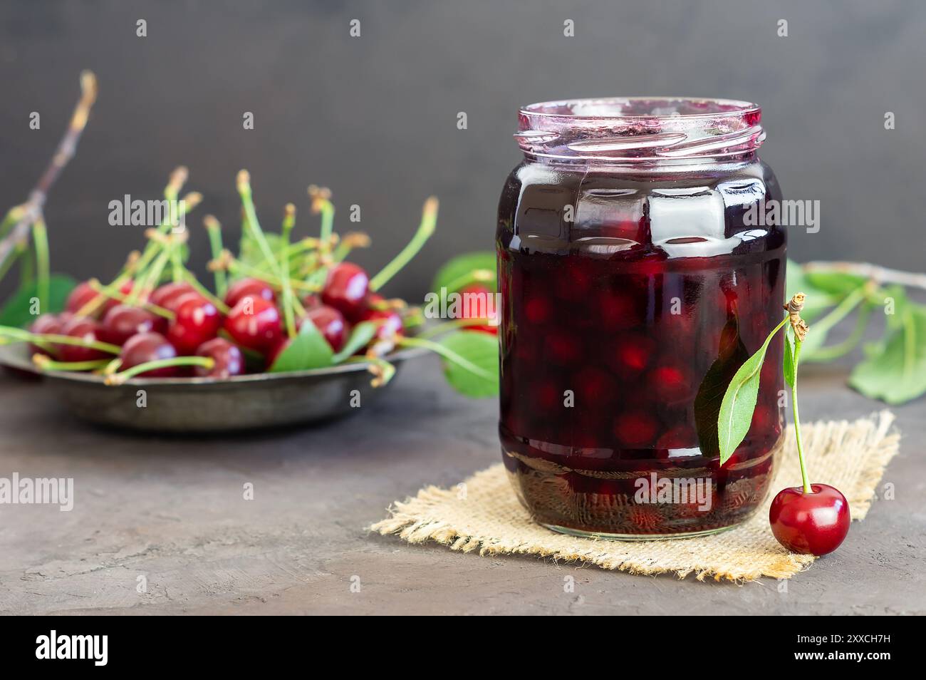 Sour cherry jam in glass jar or bowl with fresh raw sour cherries Stock Photo