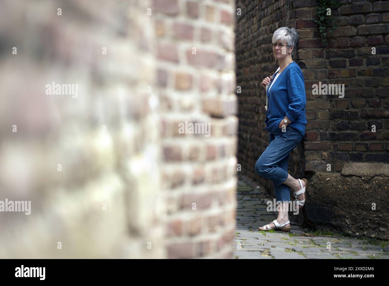 Woman standing by an old stone wall in a narrow alley Stock Photo - Alamy