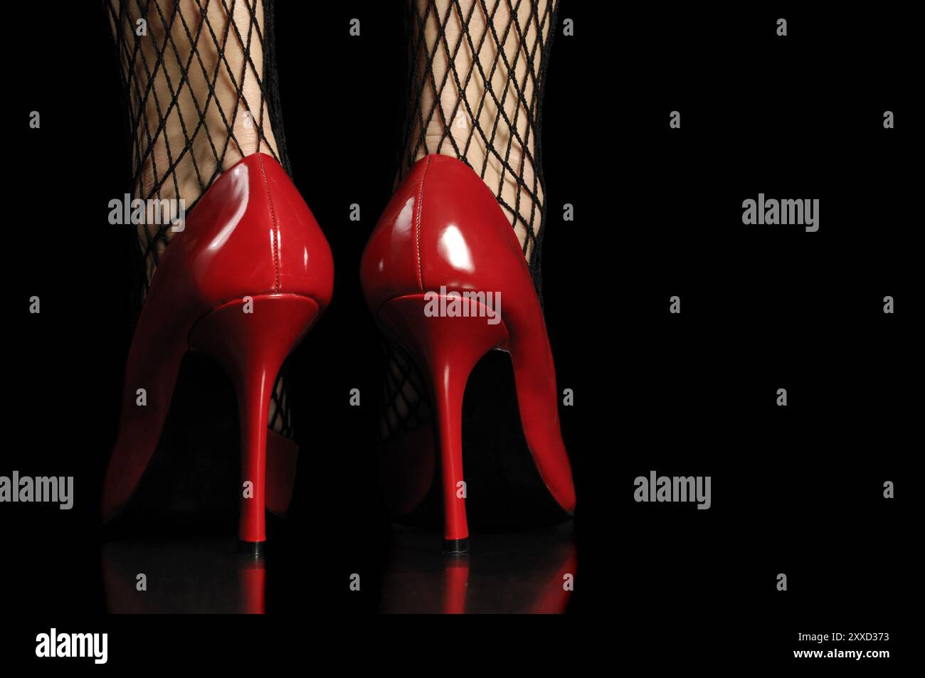Woman in fishnet stockings and red high heel shoes isolated on black ...