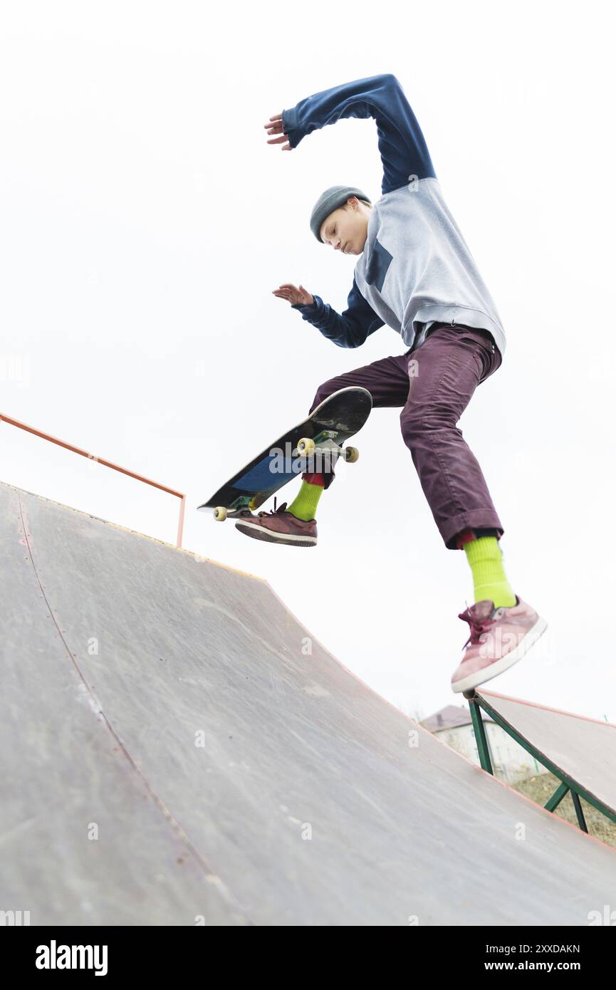 The teenager skateboarder in the cap does a trick with a jump on the ...