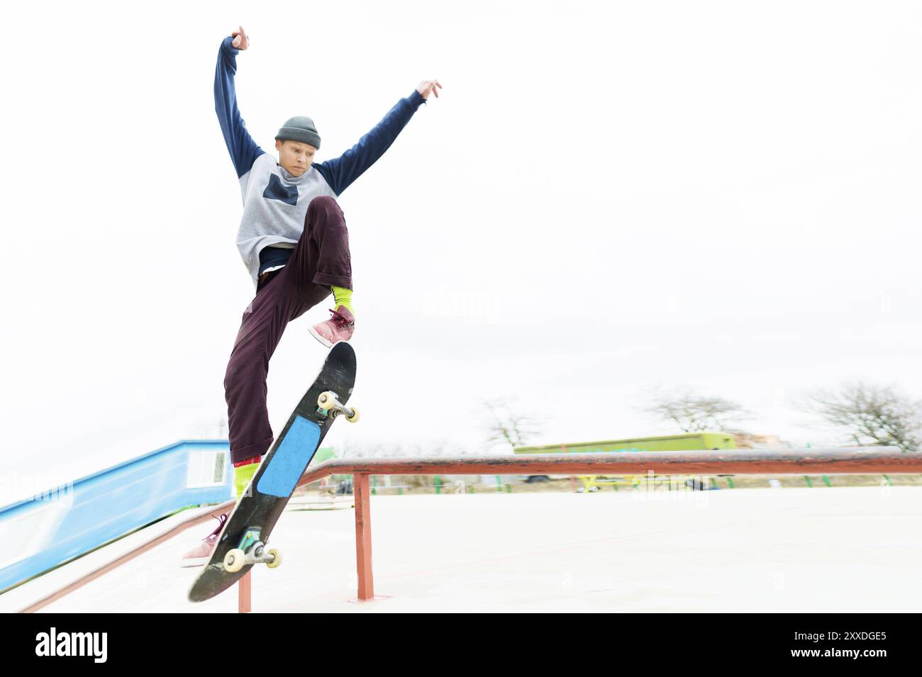 A young teenager, a skateboarder, does a trick on the railing in a ...