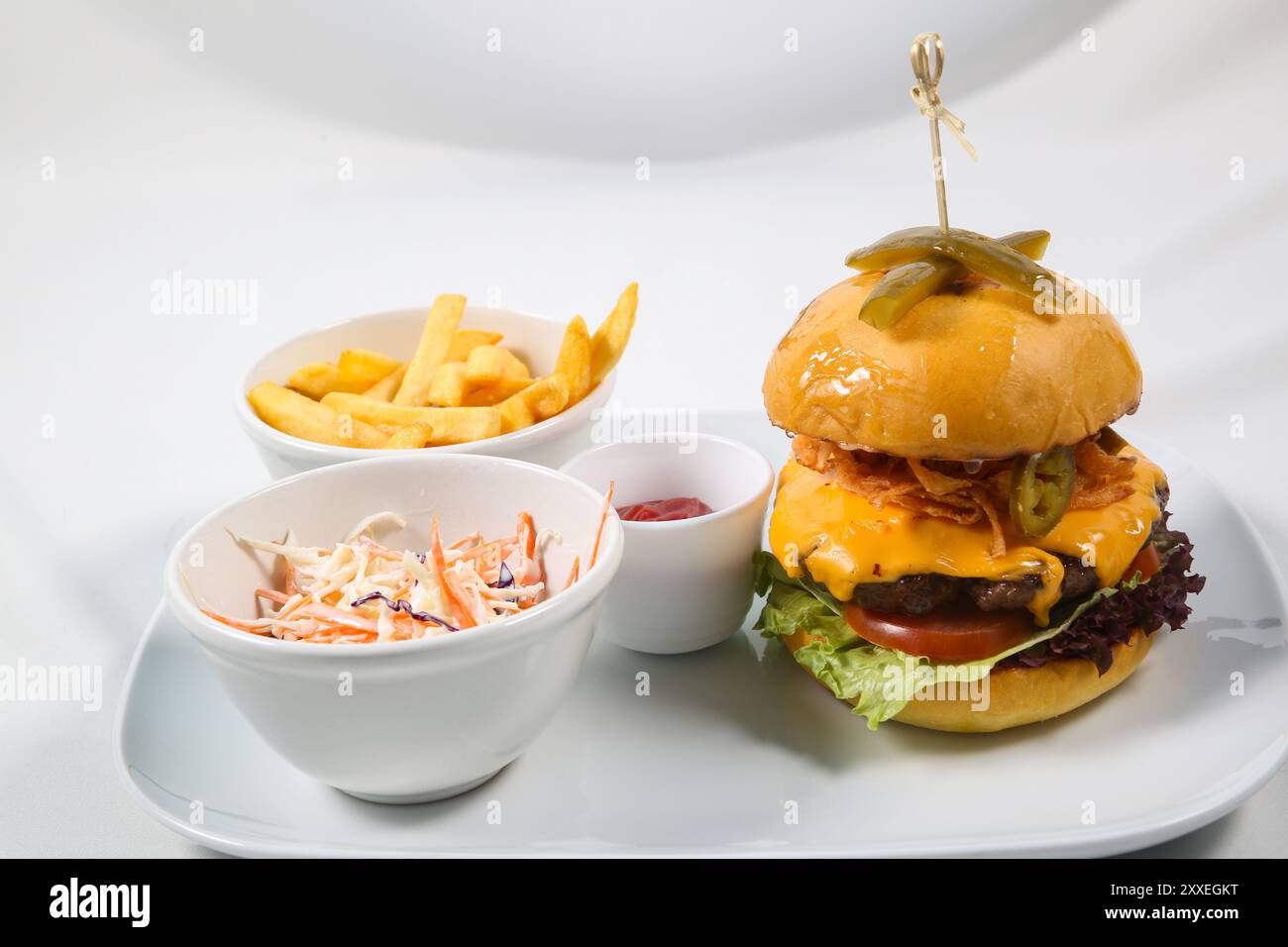 Burger with fried potatoes and tomato sauce on restaurant table. Cheeseburger, beef burger with cheese, bacon, tomatoes, cucumber, onion and lettuce Stock Photo