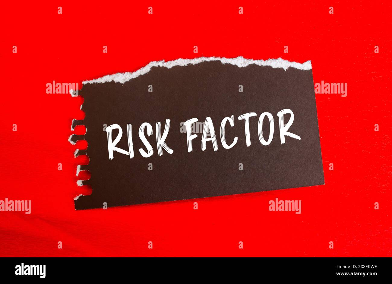 Risk factor message written on ripped torn black paper piece with red ...