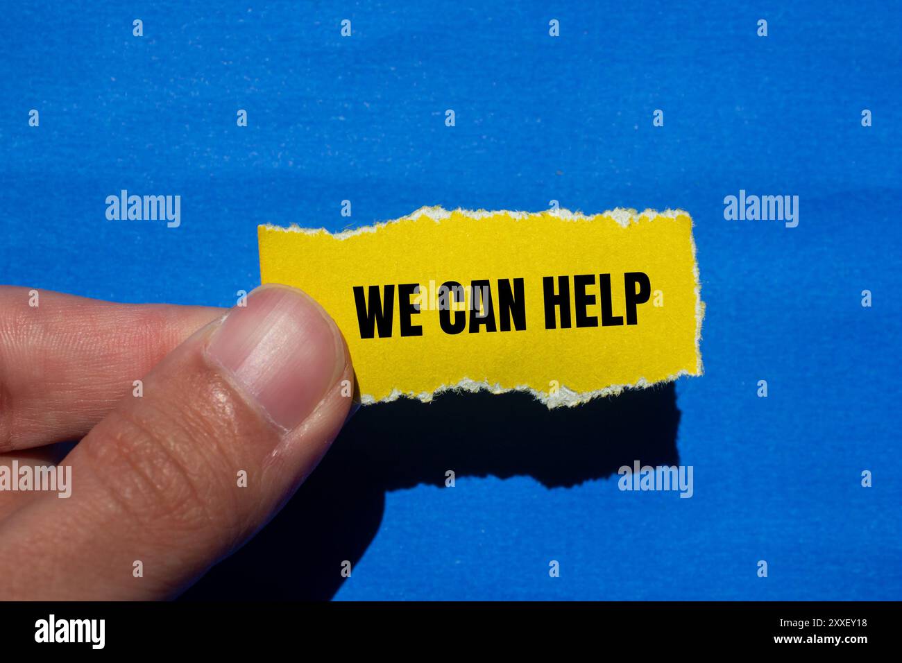 We can help message written on ripped torn yellow paper with blue ...