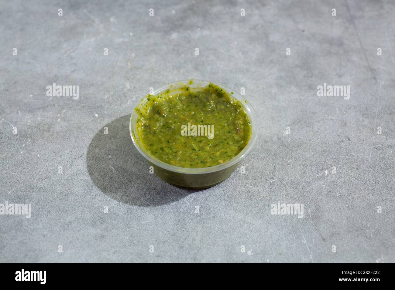 A view of a condiment cup of green sauce. Stock Photo