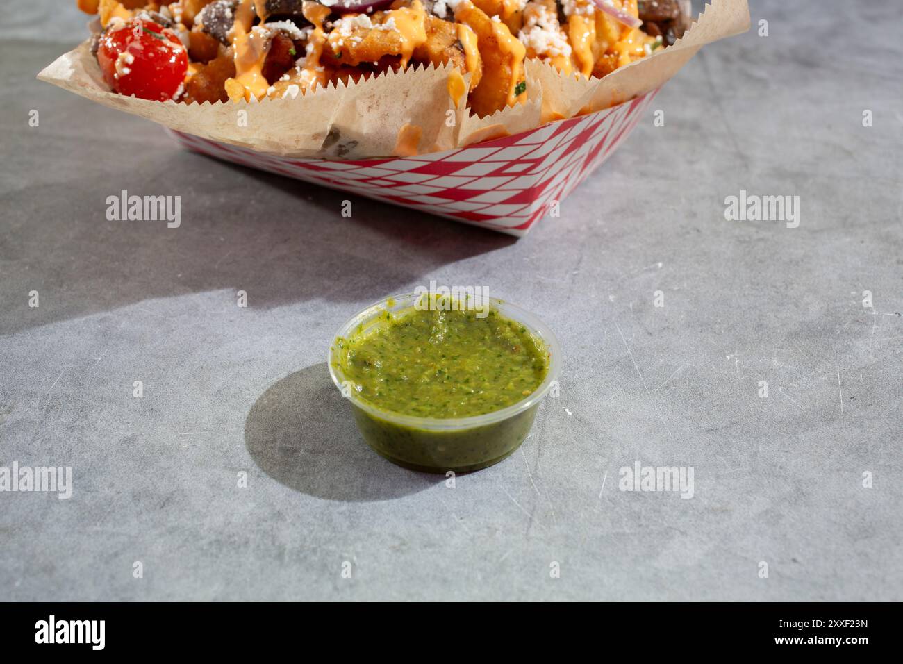 A view of a condiment cup of green sauce. Stock Photo