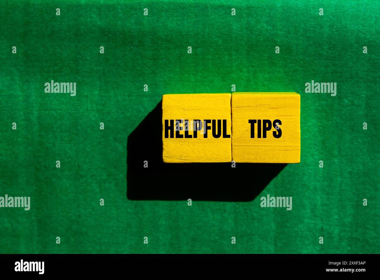 Helpful tips message written on yellow wooden cubes with green background. Conceptual helpful tips symbol. Copy space. Stock Photo