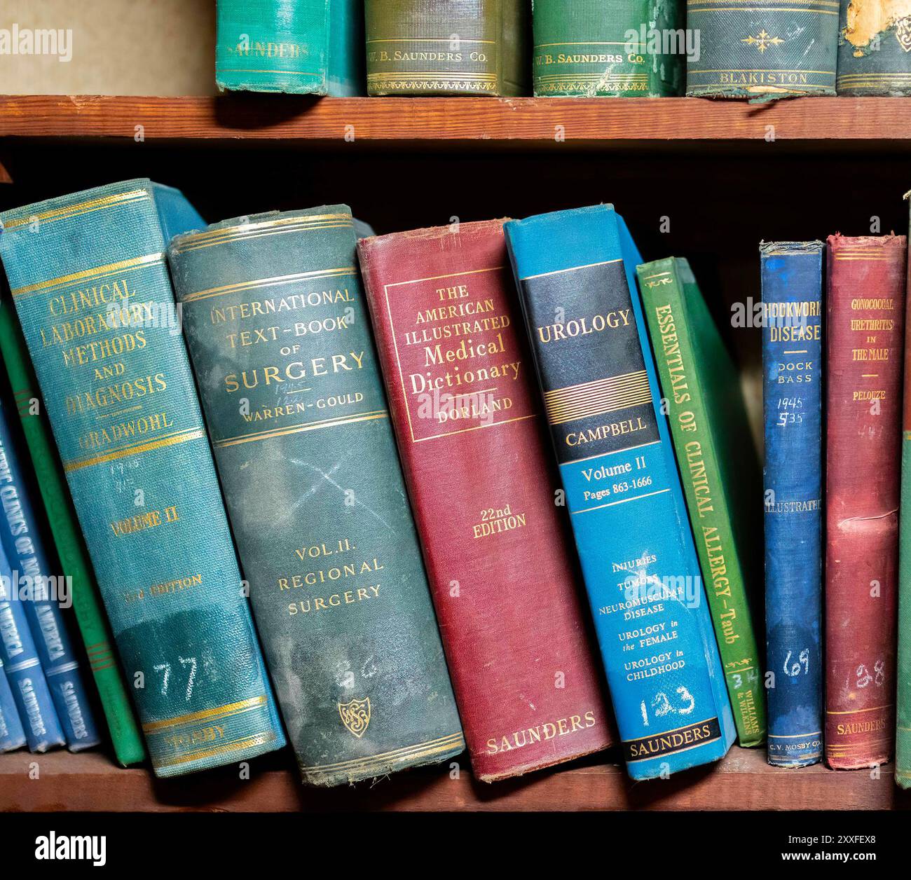 A collection of vintage and classic medical and scientific textbooks neatly arranged on a wooden bookshelf Foley medical museum alabama usa Stock Photo