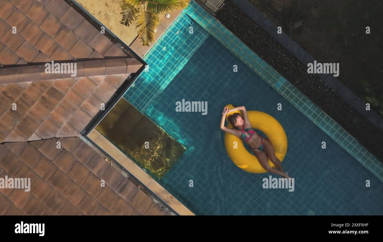 Aerial view of a tourist relaxing on a yellow inflatable ring in a ...