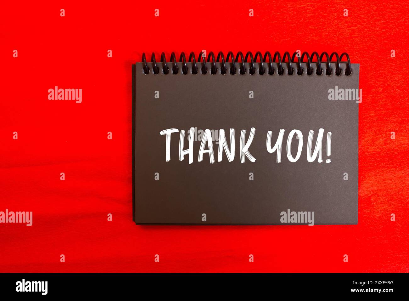 Thank you message written on black notebook page with red background ...