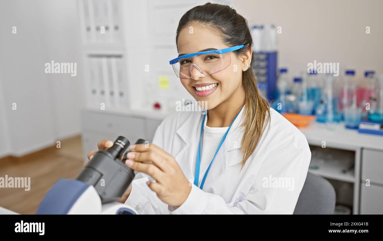 A cheerful hispanic woman scientist in a lab coat examines a sample ...