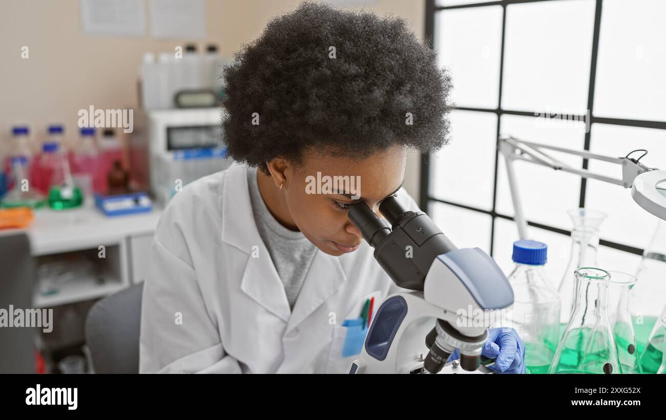 Black woman scientist analyzing samples under a microscope in a ...
