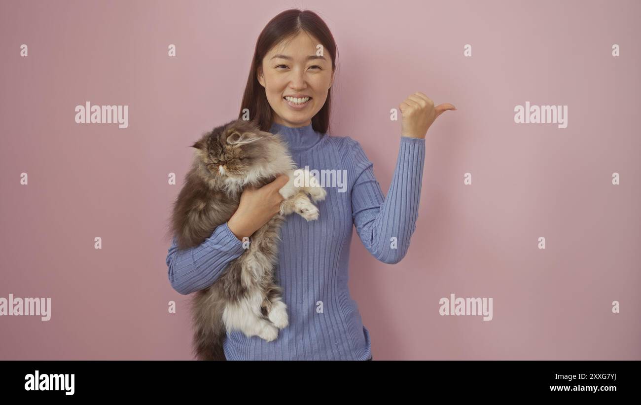 A young chinese woman in a blue sweater holding a fluffy cat stands in ...