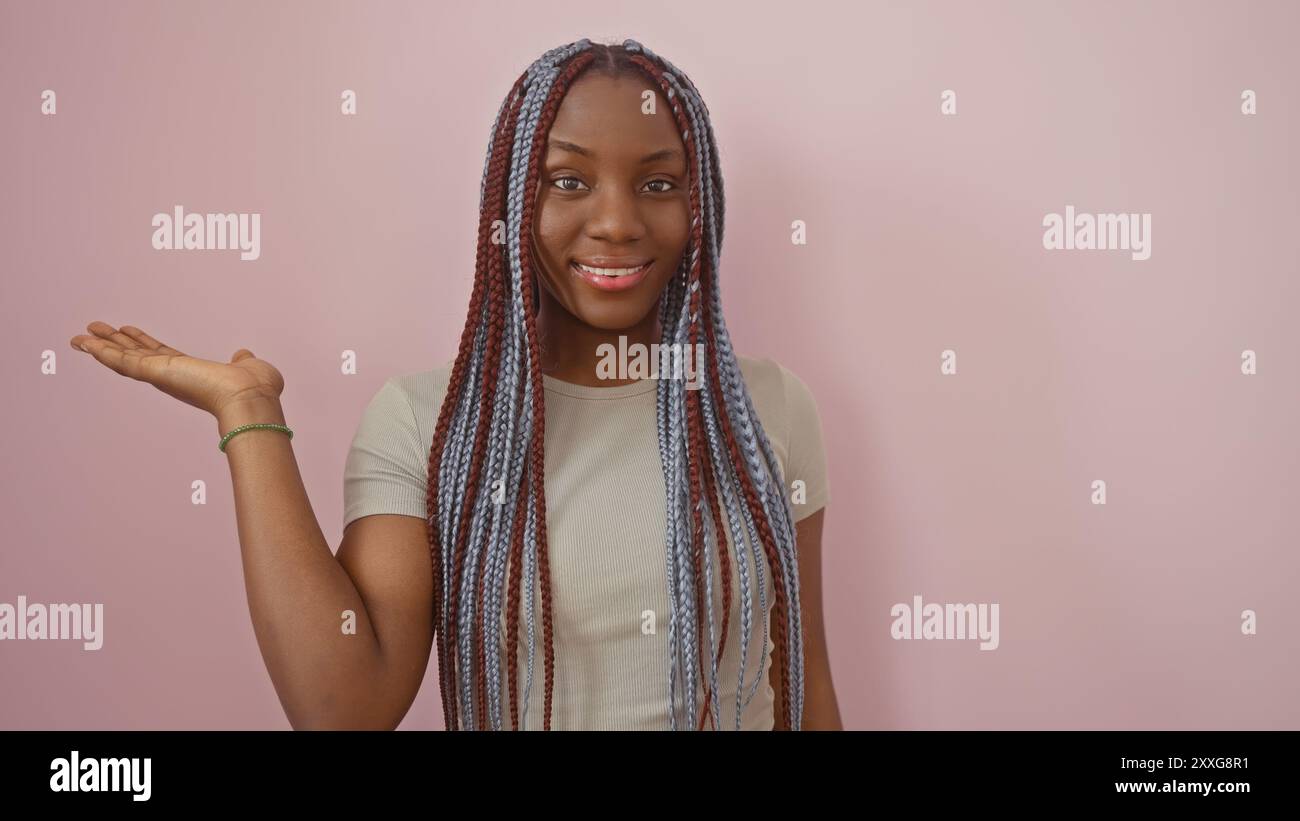 A smiling african american woman with braids presenting against a pink ...
