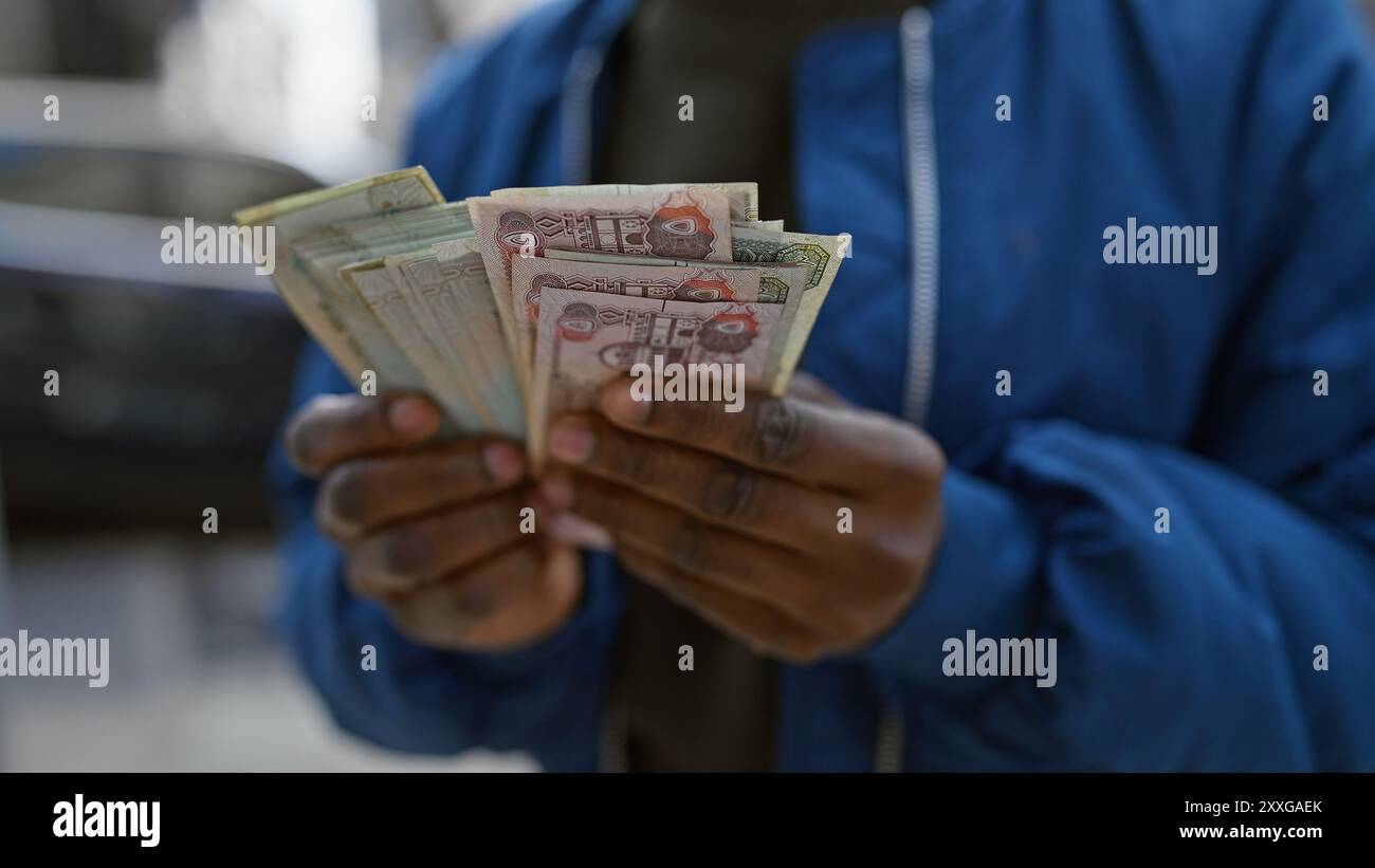 African woman counting dirhams outdoors in an urban setting Stock Photo ...