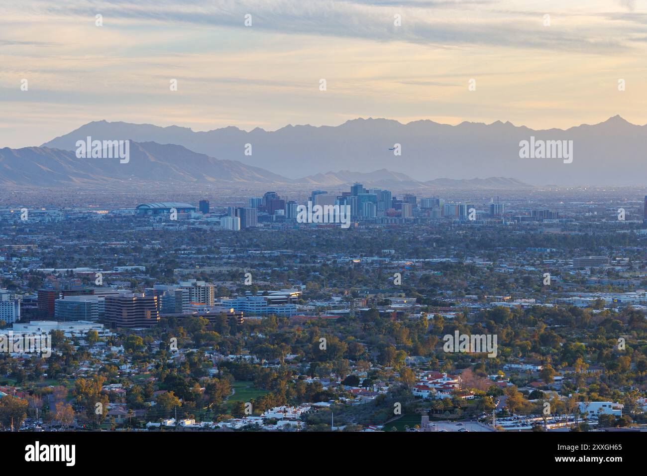 Majestic Sunset Over Phoenix: A Stunning Aerial View of Arizona's Bustling Metropolis Against the Backdrop of Desert Mountains and a Serene Sky. Stock Photo