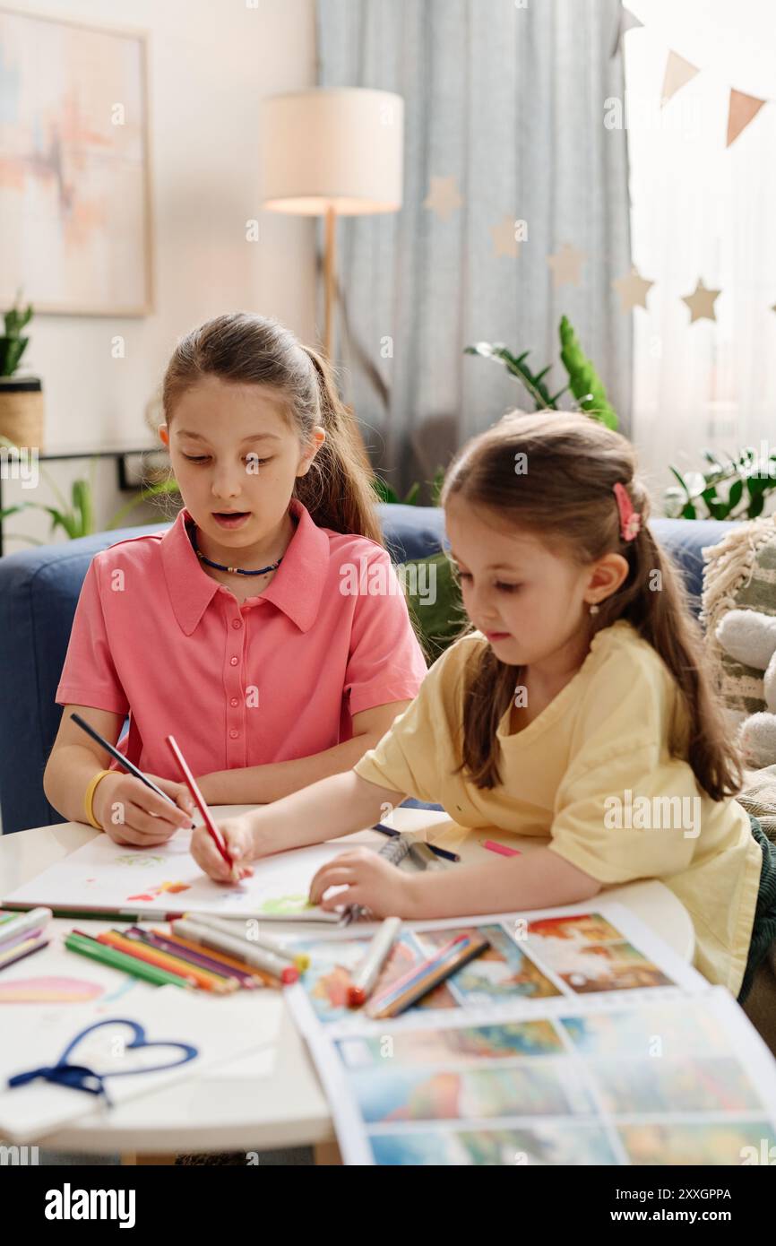 Two young girls engaging in drawing and coloring activities at home ...