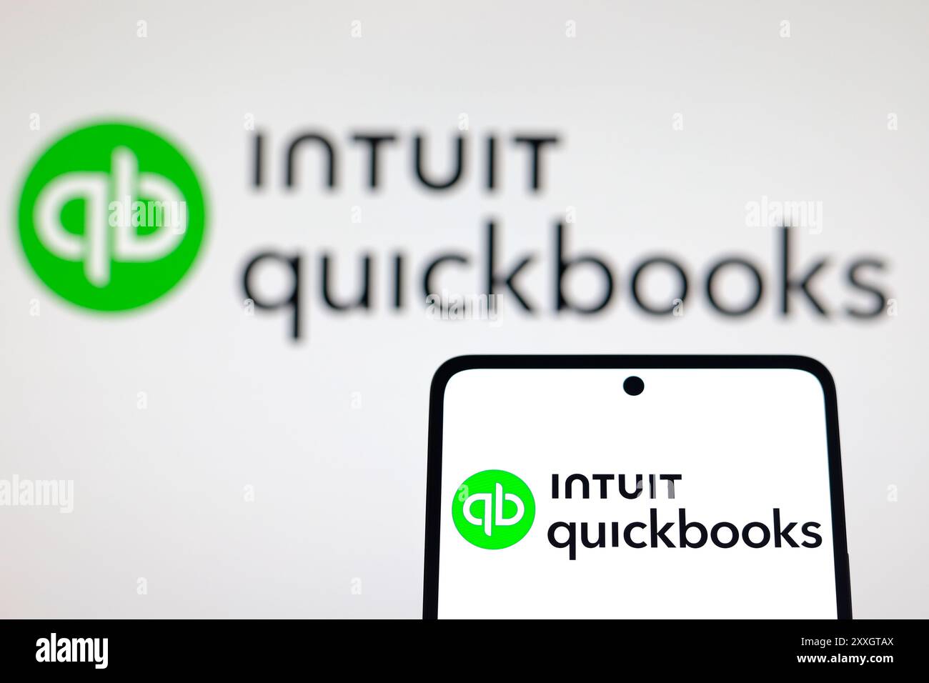 In this photo illustration, the QuickBooks logo is displayed on a smartphone and in the background. Stock Photo