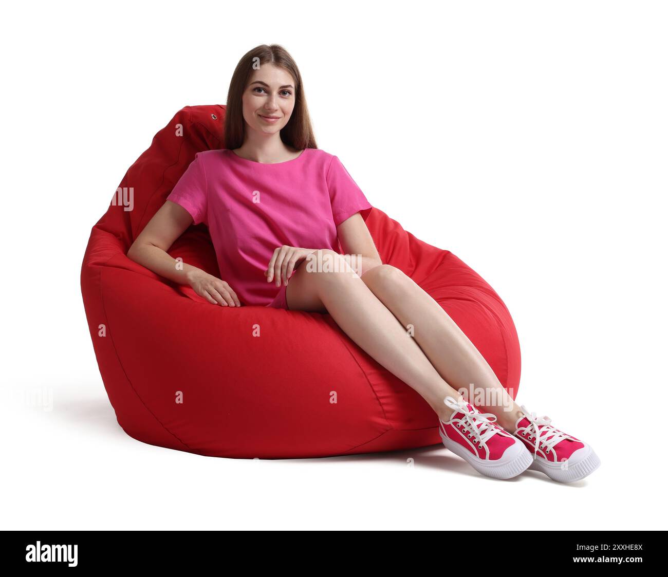 Beautiful young woman sitting on red bean bag chair against white ...