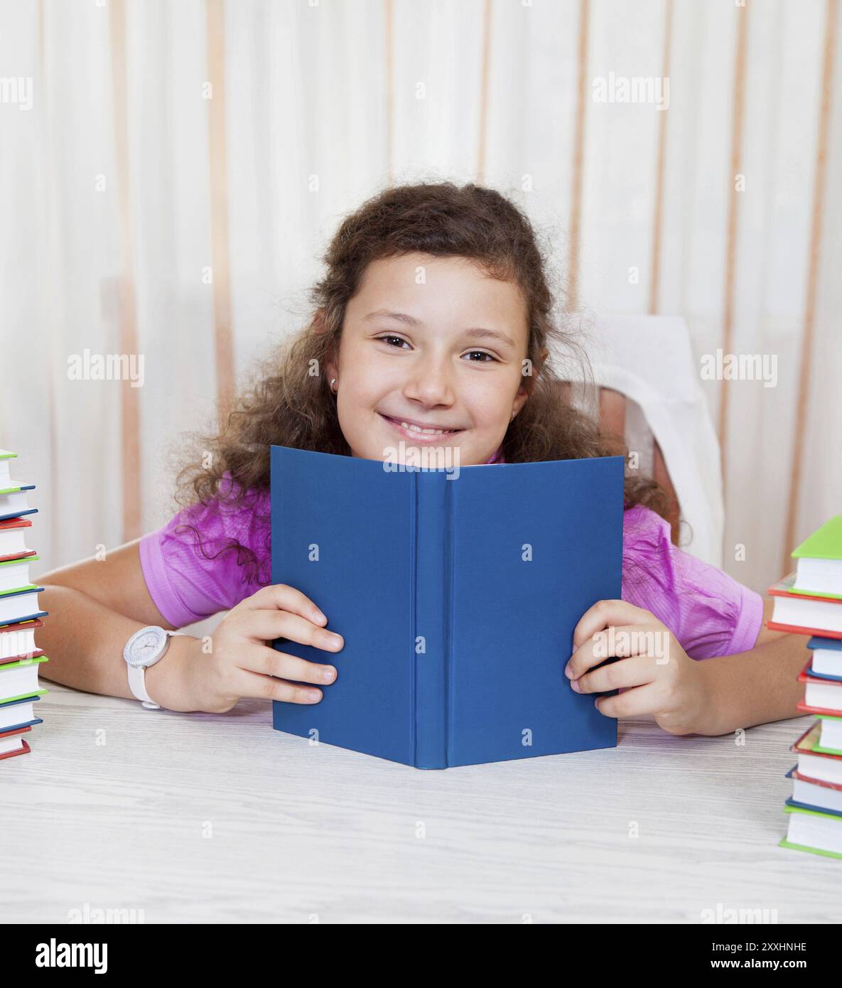 Little brunette smiling girl with piles of books Stock Photo - Alamy