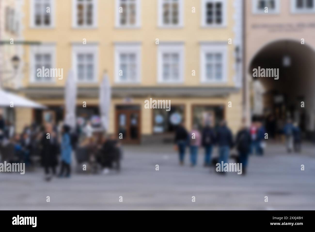 A blurred background shows a European city street scene with people ...