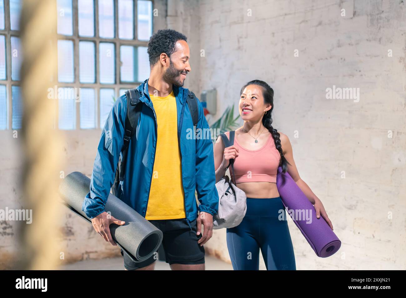 Cheerful male and female athlete standing together at gym. Smiling woman and male friends. Stock Photo