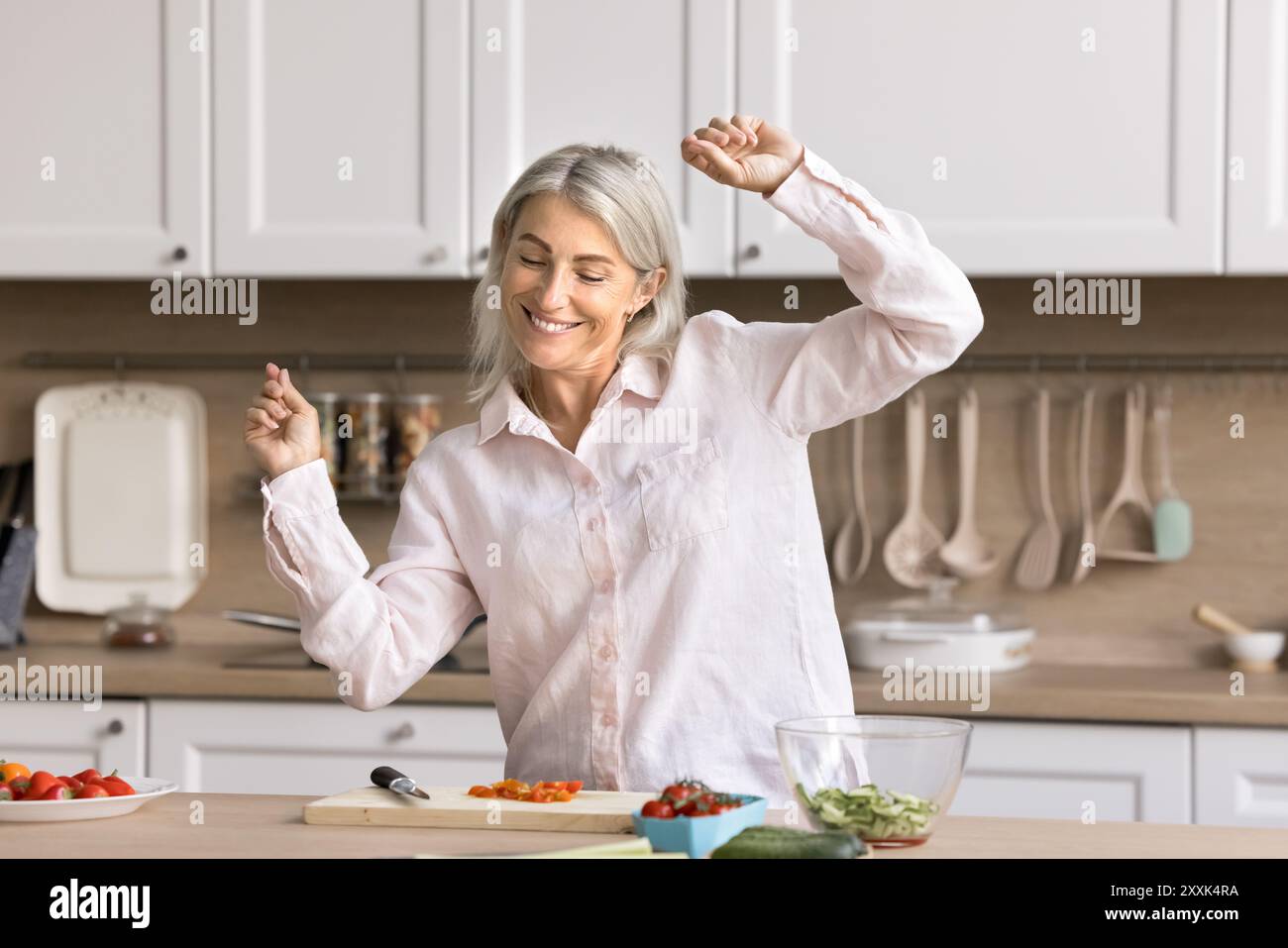 Happy mature woman dance and cook in the kitchen Stock Photo