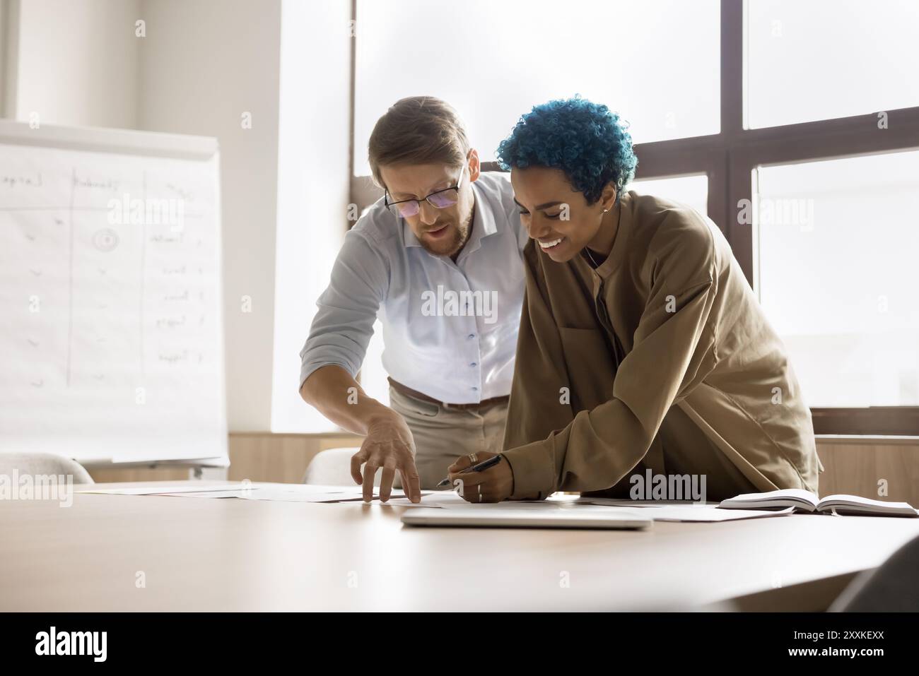 Two colleagues standing at desk, examining printed documents Stock Photo