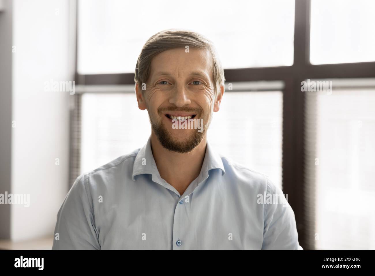 Businessman casually dressed in shirt, smiling confidently posing for camera Stock Photo