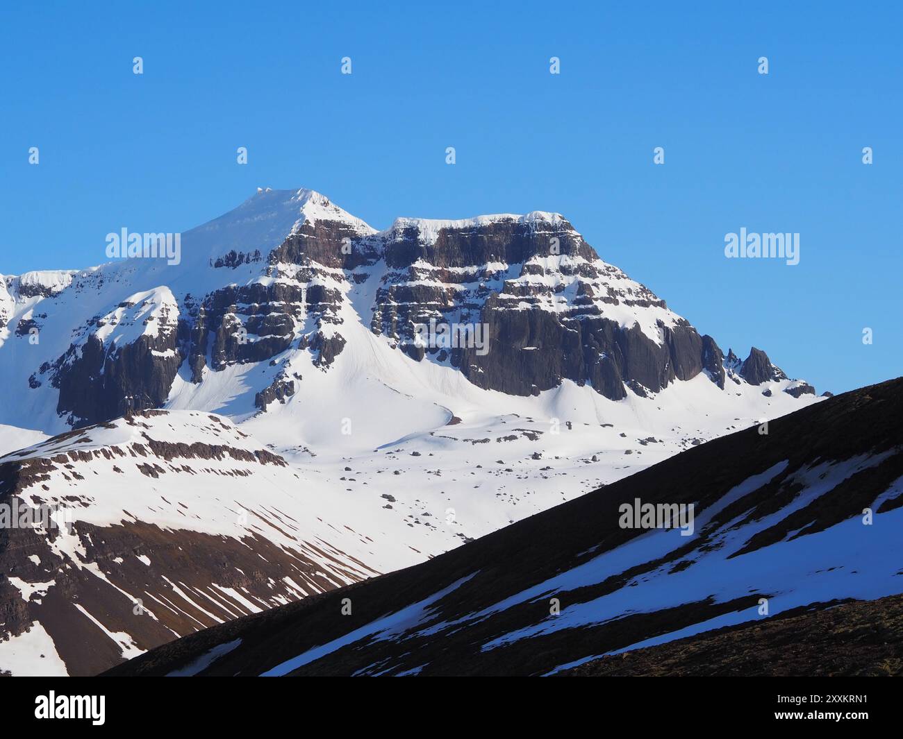 Snow-capped mountain peaks stand majestically under a clear blue sky ...