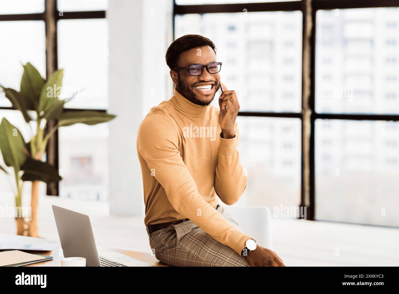 Black guy talking on phone sitting on the table Stock Photo