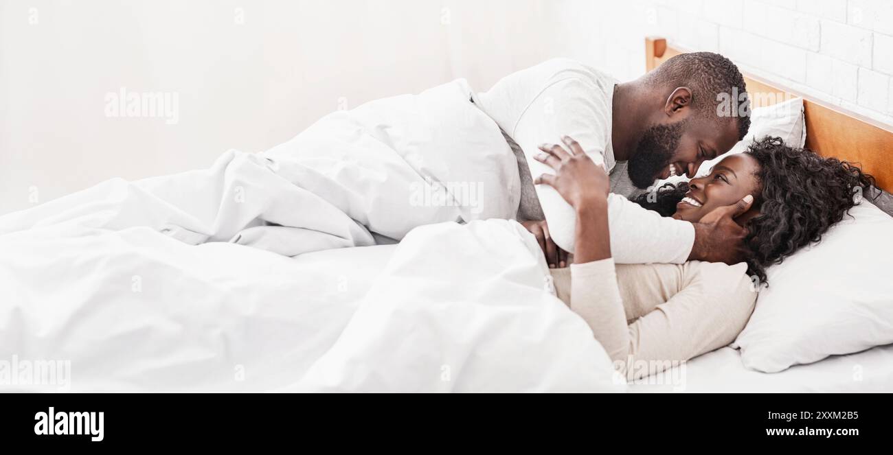 African american couple spending morning in bed, cuddling and kissing ...