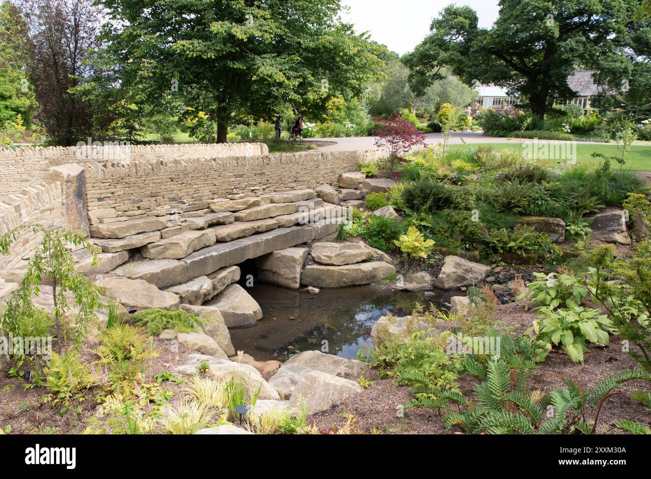 Rebuilt stone bridge over the stream at RHS Harlow Carr Stock Photo