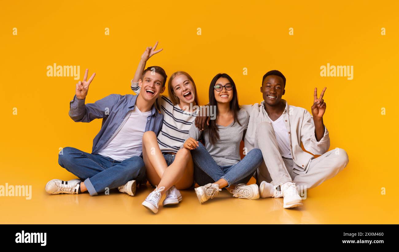 Happy students having fun over yellow studio background Stock Photo