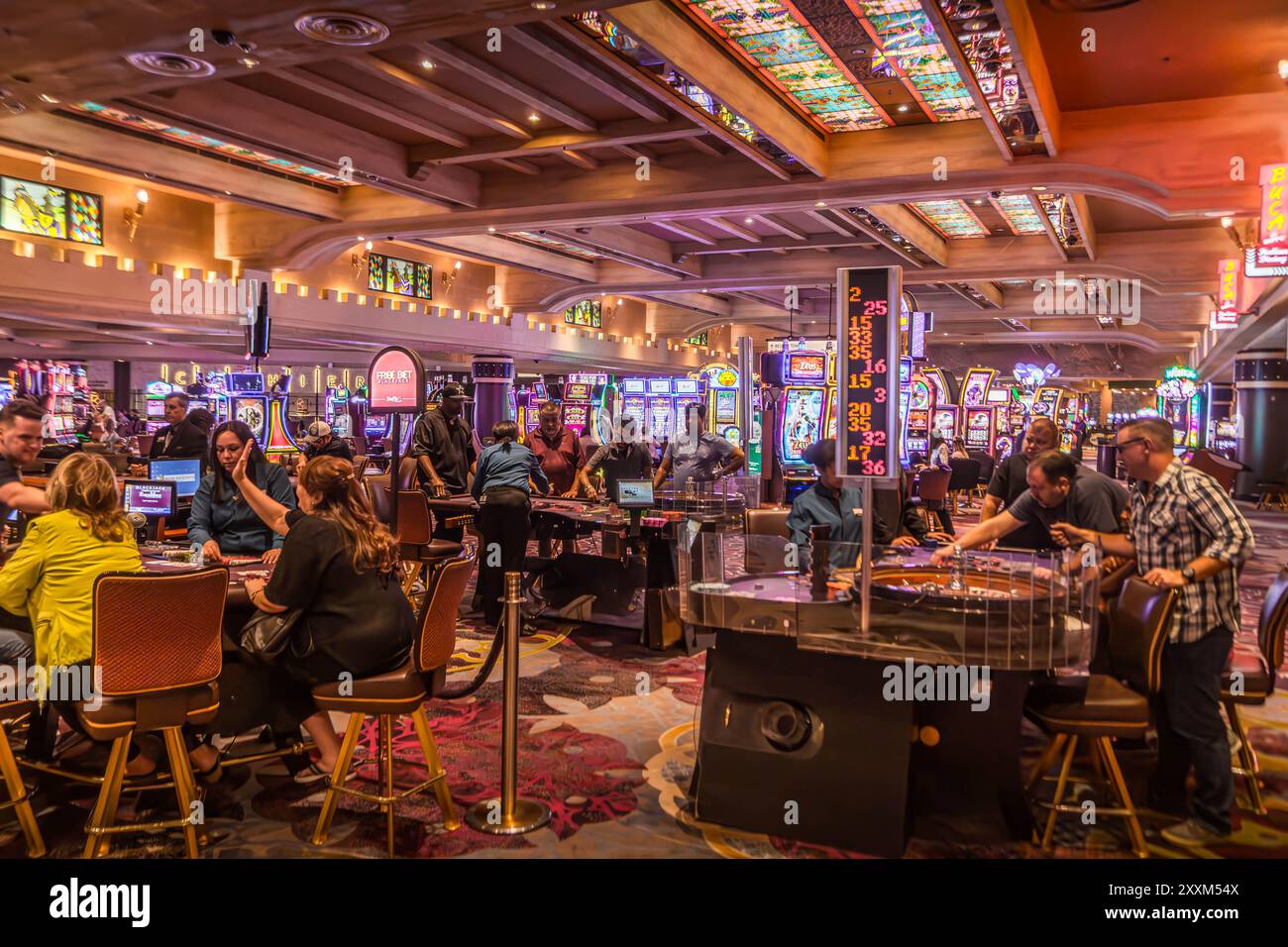 The casino hall with tourists at Las Vegas, a gambling capital of the USA, with the Poker, Blackjack, Roulette tables and slot games. Stock Photo