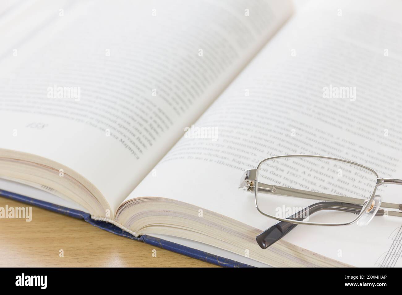 Close up of reading glasses and open book on the desk Stock Photo - Alamy