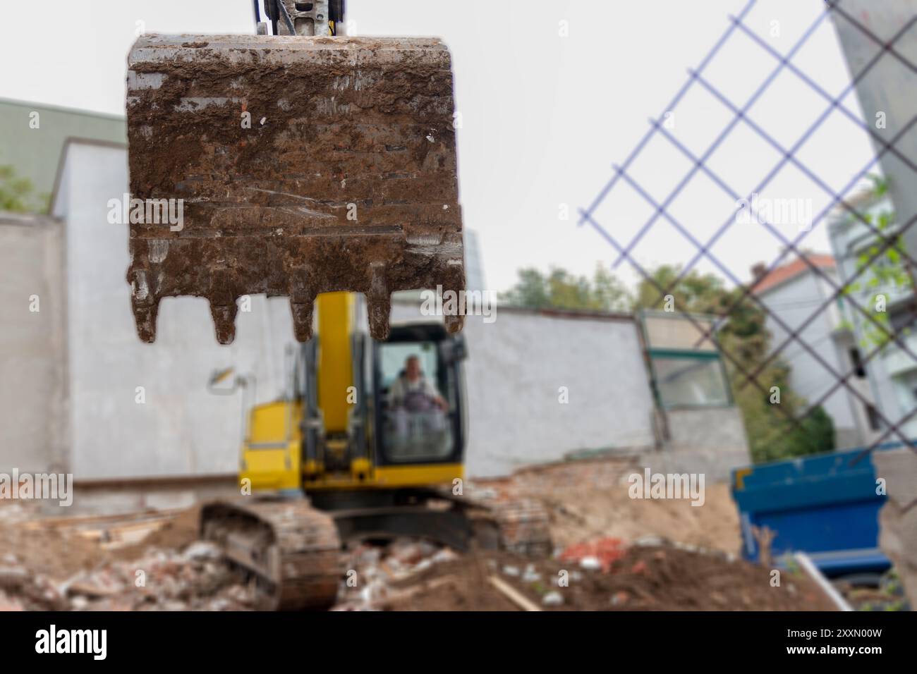 Big excavator is filling a dumper truck with soil at construction site, project in progress. Stock Photo