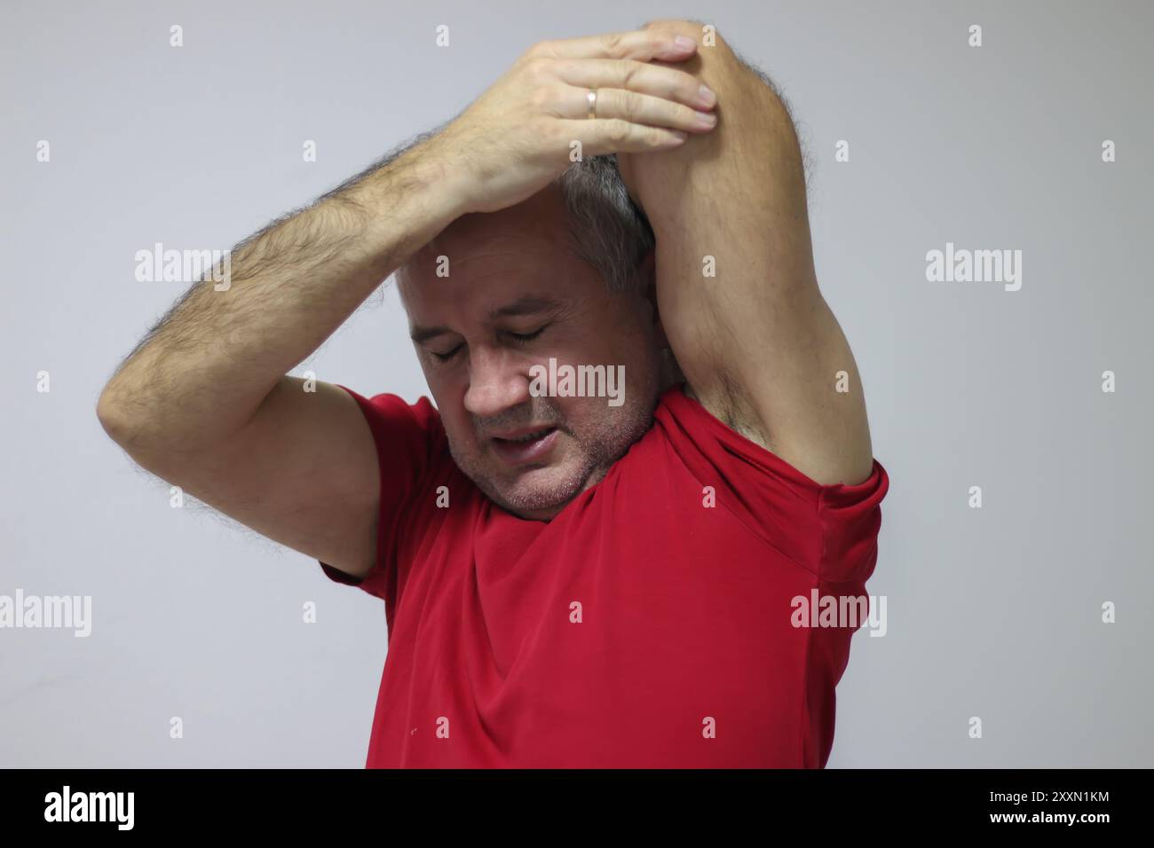 Mature man suffering from shoulder and back pain while sitting on chair ...