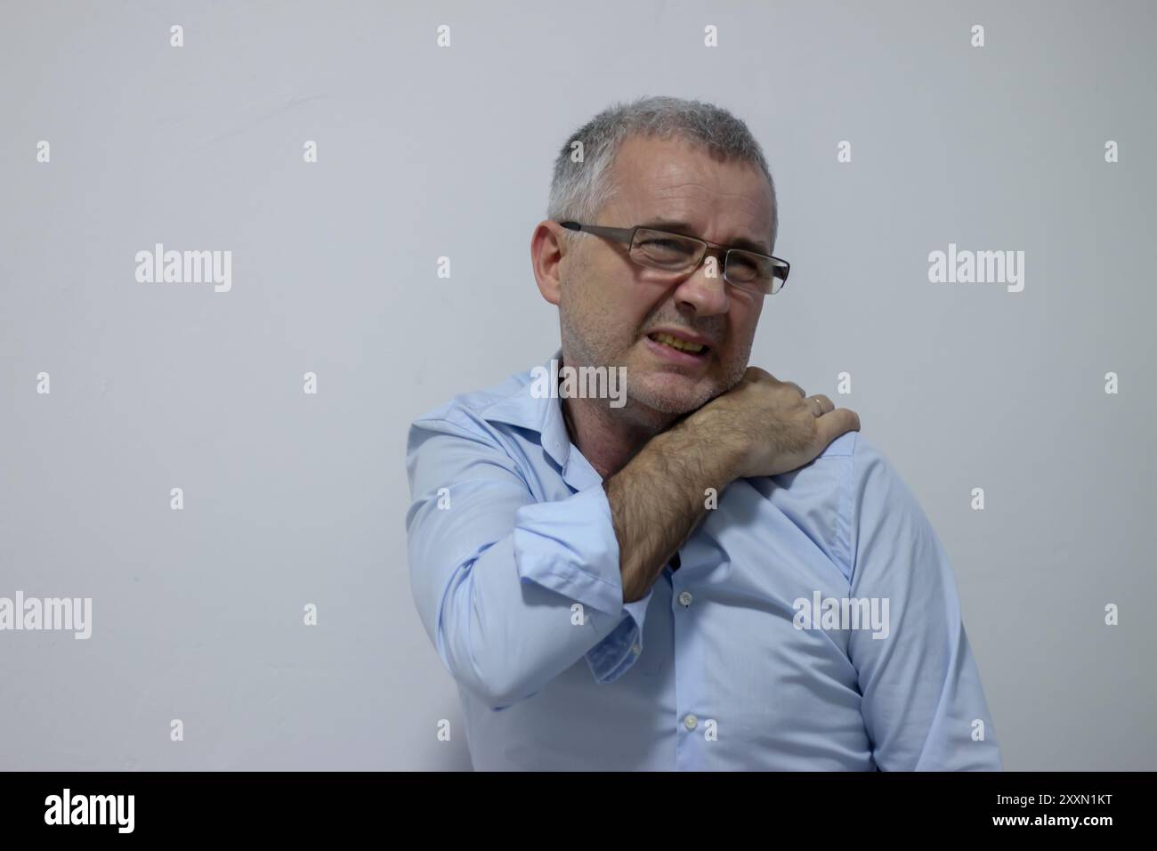 Mature man suffering from shoulder and back pain while sitting on chair ...
