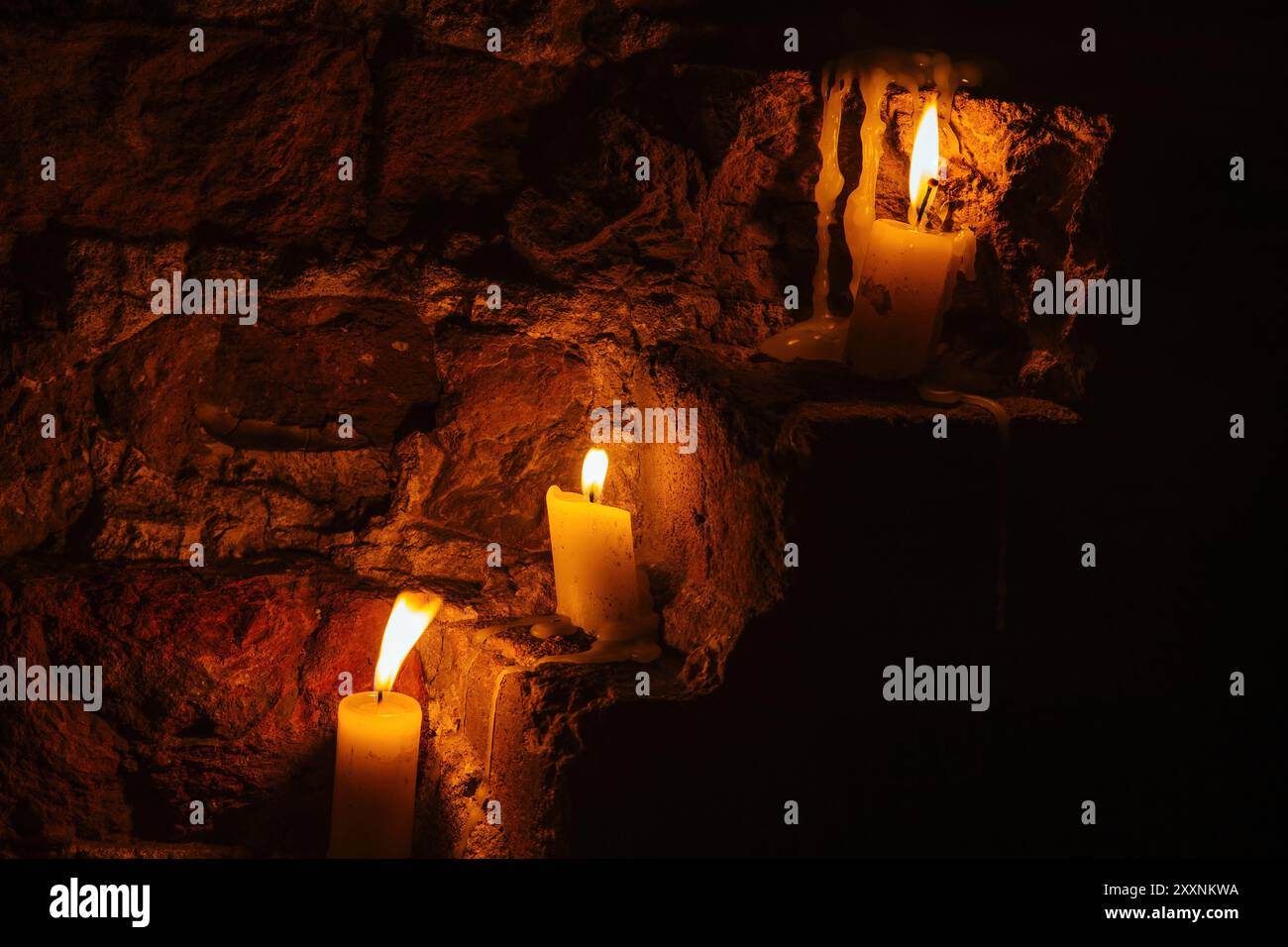 Candles on red brick wall of old castle. Stock Photo