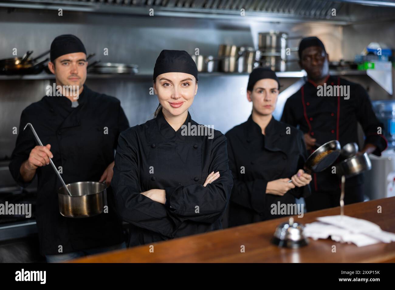 Portrait of team of cooks led by a female chef in restaurant kitchen ...