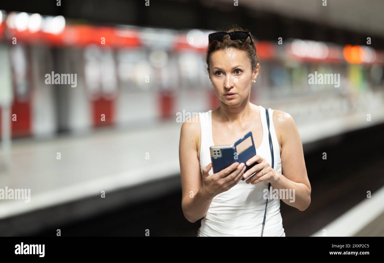 Adult woman stands at subway station with phone Stock Photo - Alamy