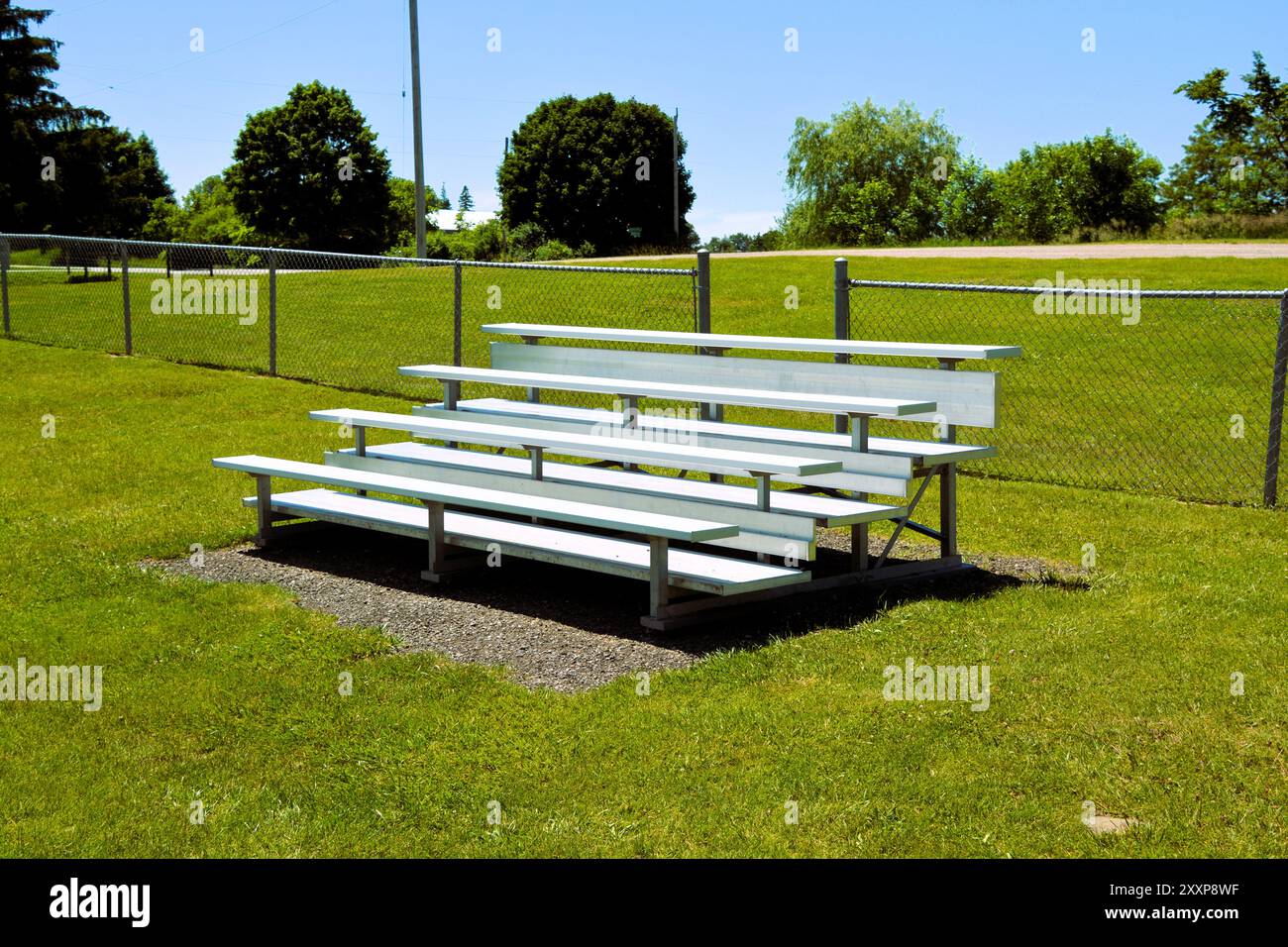 Aluminum bleachers sit empty at a soccer and sports field on a sunny summer day. Stock Photo