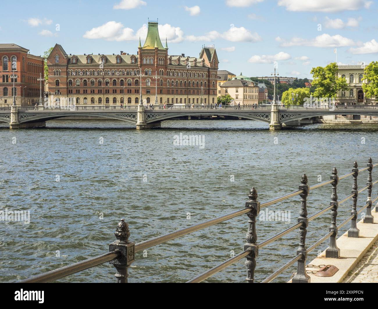 Riverside with a wrought iron railing, a bridge and historic buildings ...