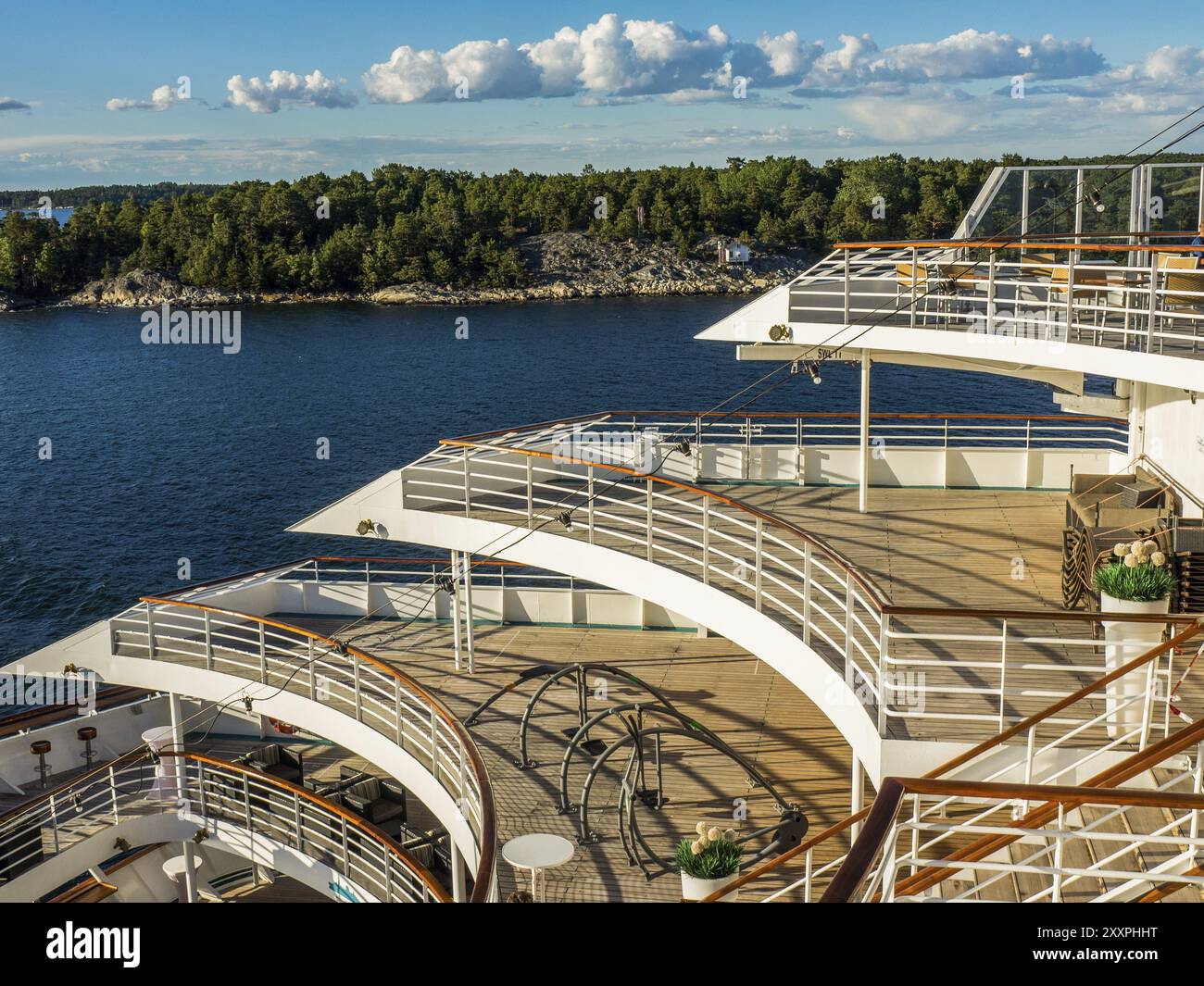 View of the deck of a cruise ship with railings and a green island in ...