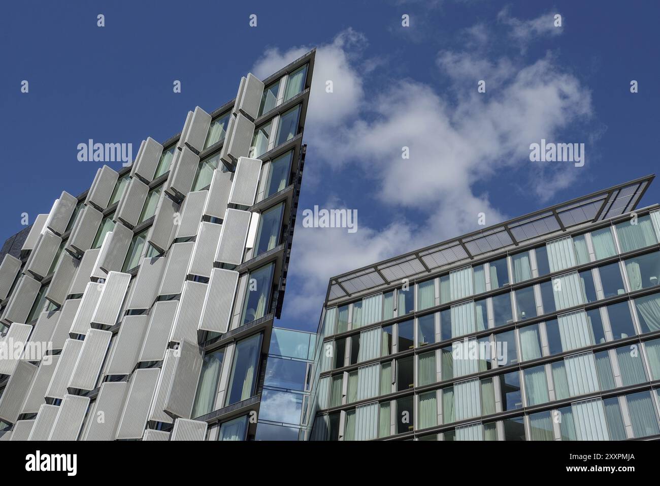 Two modern buildings with impressive glass facades under a cloudy sky ...
