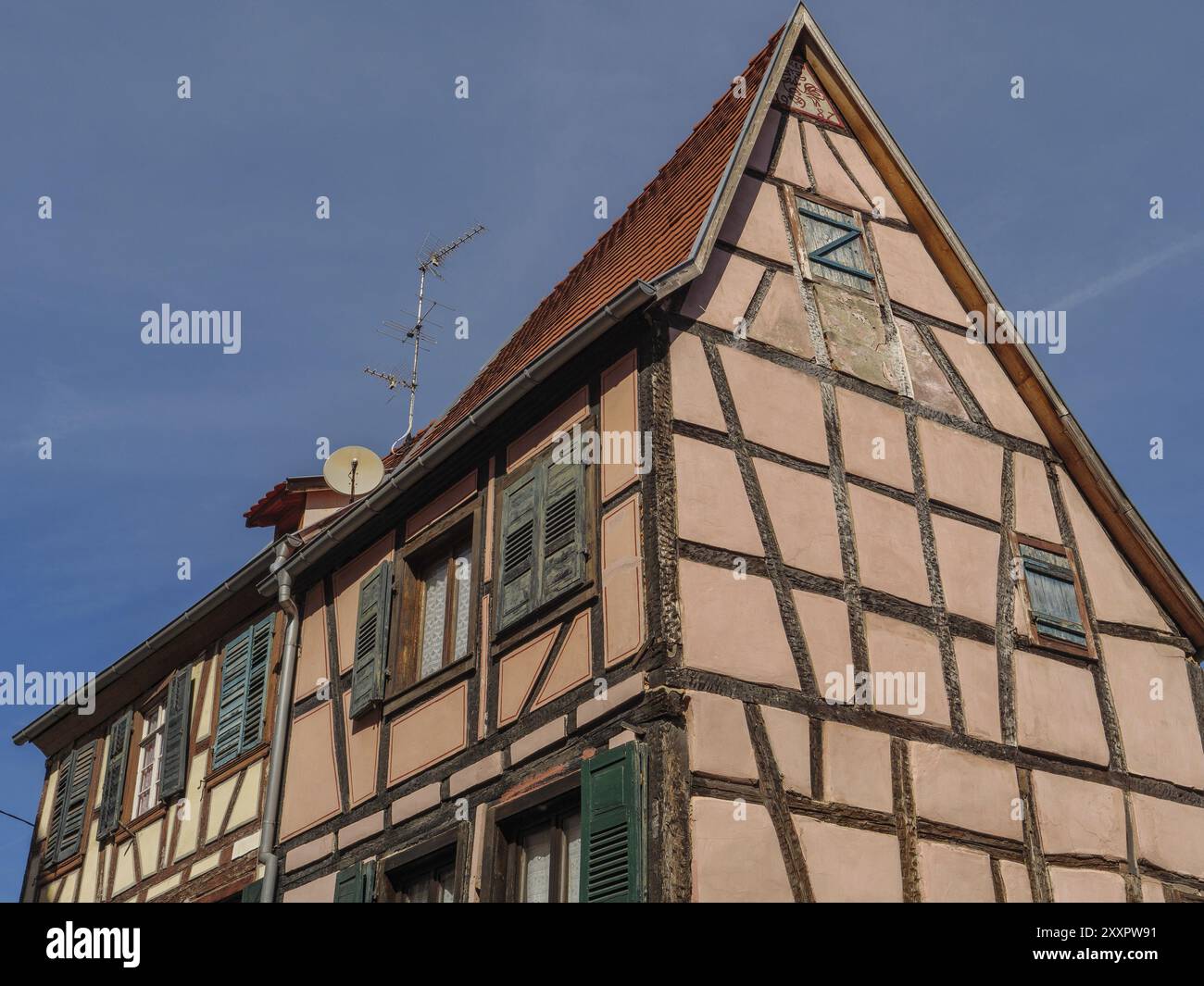 Traditional half-timbered house with exposed wooden beams, shutters and a satellite dish against a blue sky, Weissenburg, Alsace, France, Europe Stock Photo