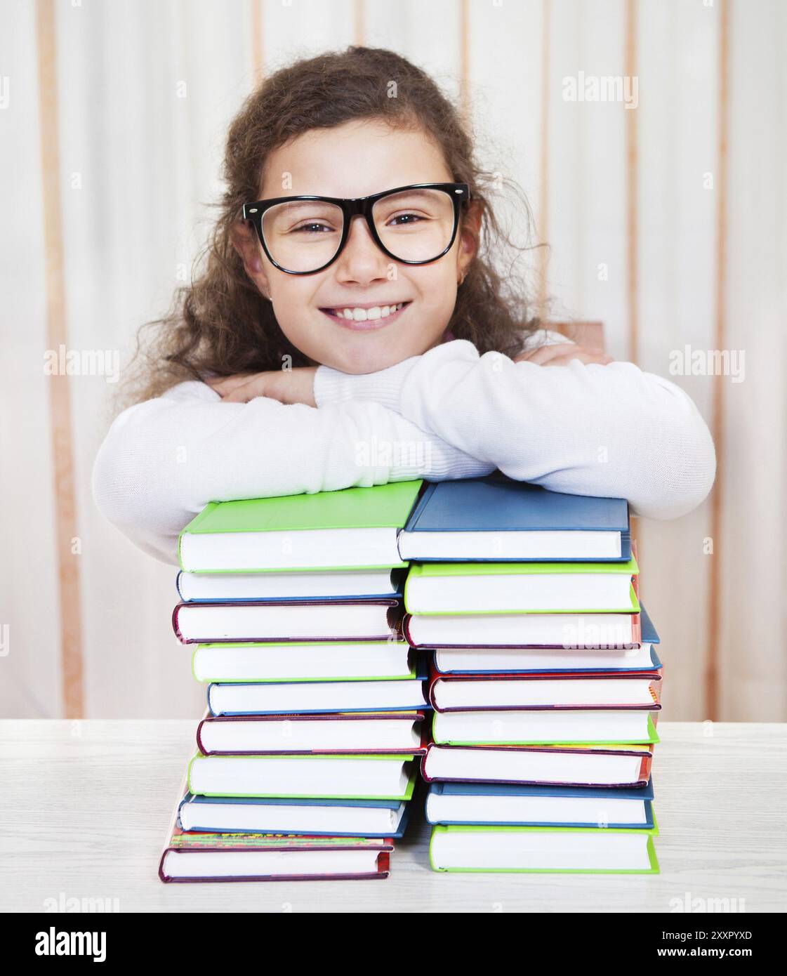 Little brunette smiling girl wearing glasses with pile of books Stock ...